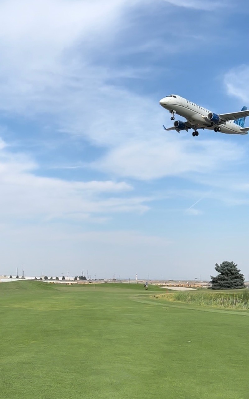 A passenger airplane with landing gear down flying low over the fairway at Sun Willows